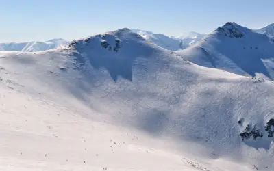 Śnieżne stoki Kasprowego Wierchu, ślady nart i pojedynczy narciarze. Kasprowy Wierch skipass to klucz do tej zimowej przygody.