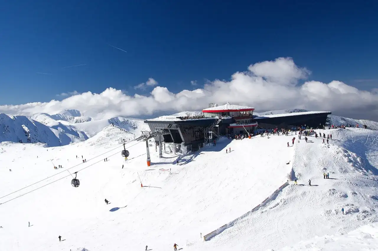 Słoneczny dzień na Chopoku, gdzie narciarze szusują po stokach, a kolejka gondolowa wwozi ich na szczyt.