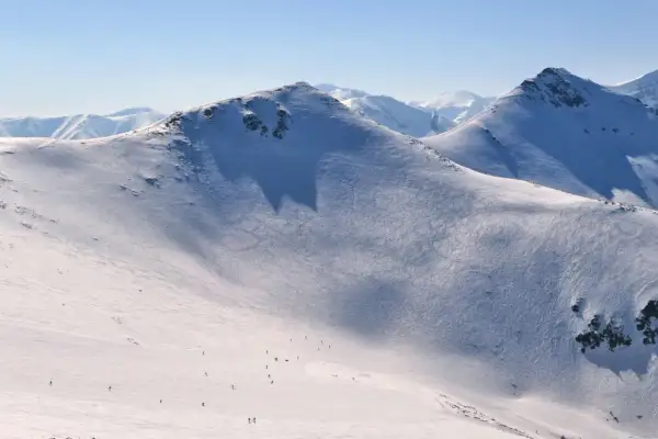 Śnieżne stoki Kasprowego Wierchu, ślady nart i pojedynczy narciarze. Kasprowy Wierch skipass to klucz do tej zimowej przygody.