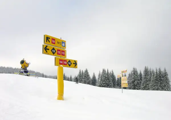 Żółte znaki na stokach narciarskich wskazują trasy: 12A, 12, 11B, 11E, 11D, 16A, 16B, 16C.